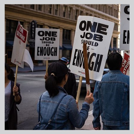 Union demonstrators march with signs saying one job should be enough